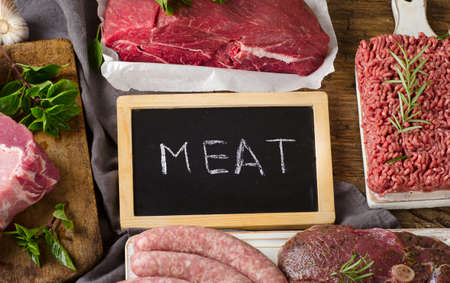 Different types of fresh raw meat on dark wooden background. Top view
