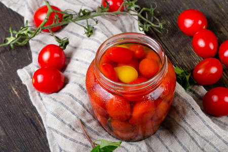 Fresh and canned tomatoes on a wooden boardの写真素材