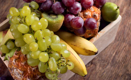 Fresh different fruits in wooden box. Top viewの写真素材