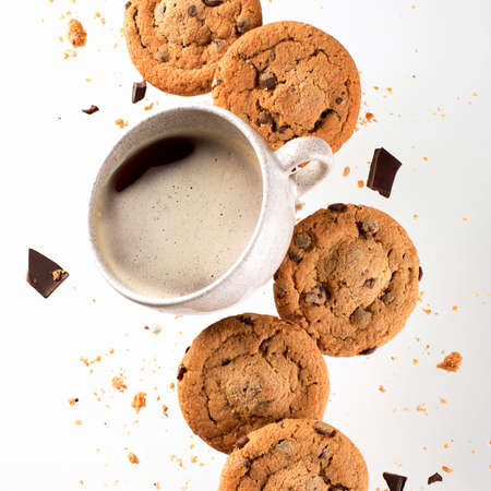 Cup of coffee with flying cookies. Chocolate chips falling in motion
