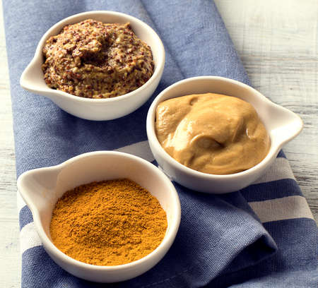 Different kinds of mustard on white wooden table. Top viewの写真素材