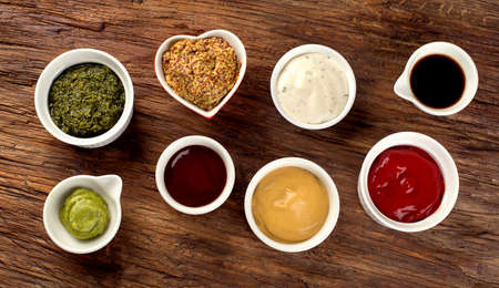 Bowls of various sauces on rustic wooden background. 