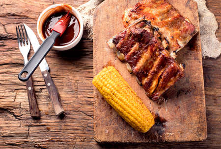 Pork ribs with corn on a wooden board. American food. View from above.の写真素材