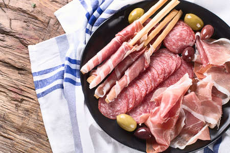 Plate with prosciutto, salami, bread sticks and olives. Top viewの写真素材