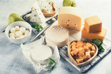 Different kinds of cheeses on rustic wooden board.