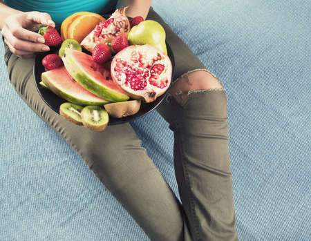 Young woman eating fresh fruits for healthy breakfast. View from above.の写真素材