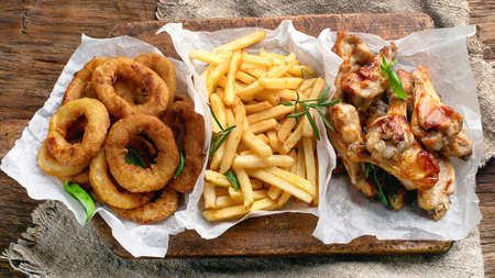 Fast food snacks - onion rings, fries and chicken wings. American food.の写真素材