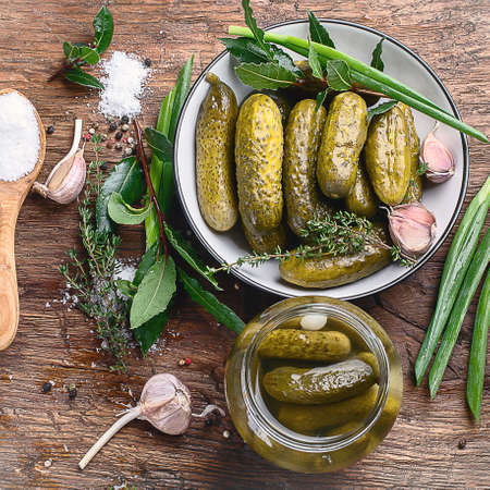 Pickled  cucumbers in bowl on wooden rustic board. Top viewの写真素材