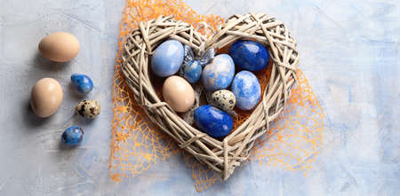 Easter eggs in heart-shaped nest. Top view with copy space.