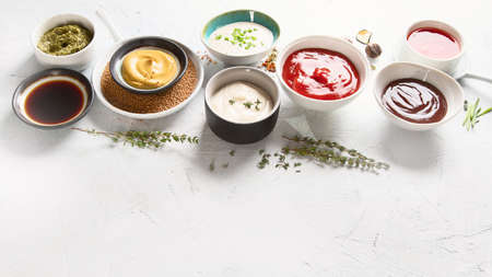 Bowls of various sauces - ketchup, mayonnaise, barbecue, soy, mustard, pesto, garlic, sweet chilli. Image with copy spaceの写真素材