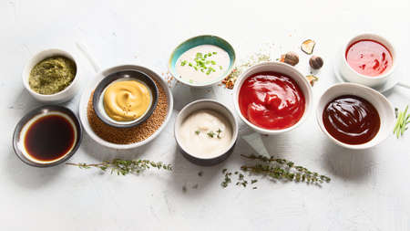 Bowls of various sauces - ketchup, mayonnaise, barbecue, soy, mustard, pesto, garlic, sweet chilli...