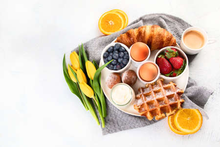 Breakfast table with eggs, berries, yogurt,waffle and croissant. Top view with copy spaceの写真素材