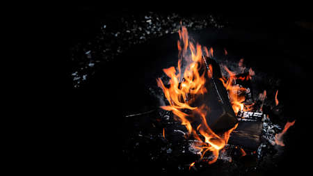 Fire flames with sparks on  coals on black background. Image with copy space