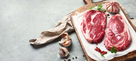 Raw beef steaks on wooden cutting board. Image with copy space