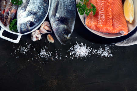 Fresh raw fish and seafood on black background. Top view with copy spaceの写真素材
