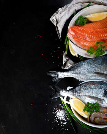 Fresh raw fish and seafood on black background. Top view with copy spaceの写真素材