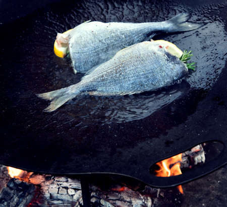 Closeup of grilled fish and shrimps on black on pan outdoors. View from aboveの写真素材