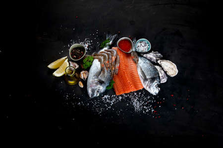 Fresh raw fish and seafood on black background. Top view with copy spaceの写真素材