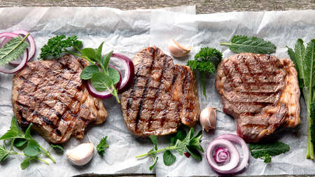 Grilled beef steaks  on wooden board. Top view with copy space