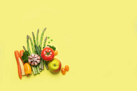 Fresh fruits and vegetables on yellow background. Healty food concept. Vegan and vegetarian diet eating. Foods high in vitamins and antioxidants. Top view with copy spaceの写真素材