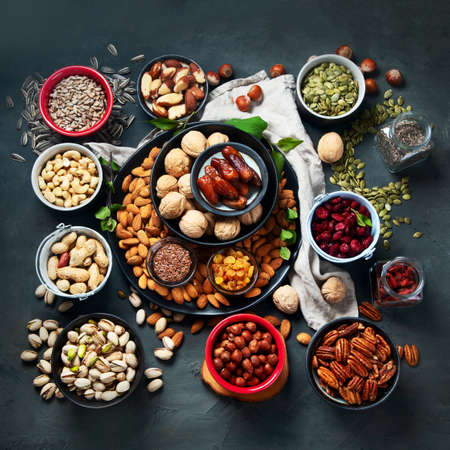 Different types of nuts, seeds and dried fruits  on black background. foods high in vegan protein,...