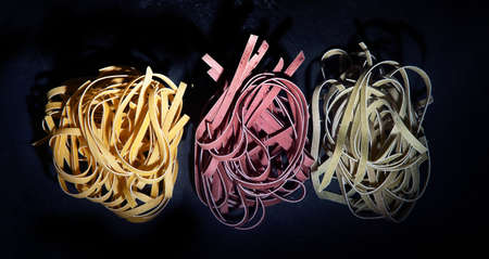 Italian raw uncooked tagliatelle pasta on black background. Top view, flat layの写真素材
