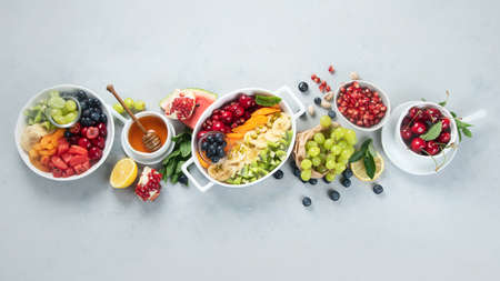 Bowl of healthy fresh fruit salad on grey background. Top view, flat lay with copy space