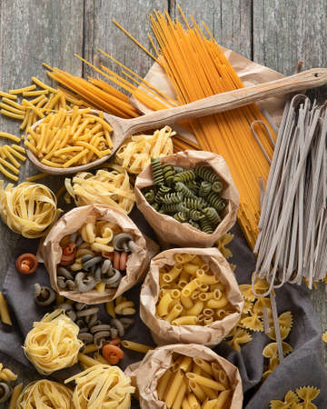 Different type of pasta on wooden rustic background. Diet food concept