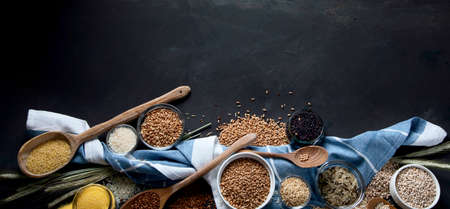 Different types of cereals in bowls on black background. Healthy nutrition eating. Top view with...