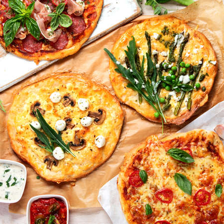 Various kinds of Italian pizza on rustic wooden table, top view, wide composition. Freshly prepared pizza, baked with herbs and vegetables, seafood, meat. Top view, flt lay.の写真素材