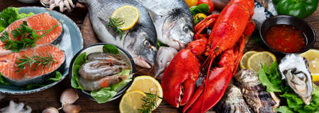 Fresh fish and seafood with herbs, spices and vegetables on rustic wooden background. Balanced diet and cooking concept. Healthy eating. Top view. Panorama, bannerの写真素材