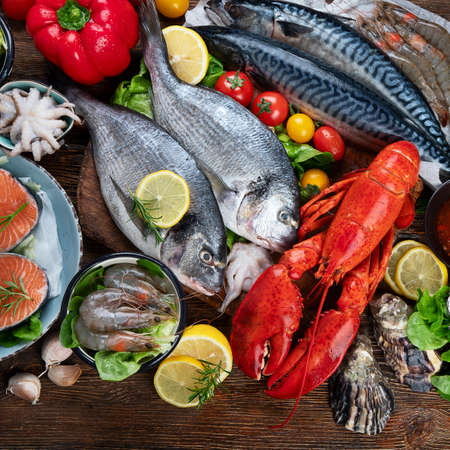 Fresh fish and seafood with herbs, spices and vegetables on rustic wooden background. Balanced diet and cooking concept. Healthy eating. Top viewの写真素材