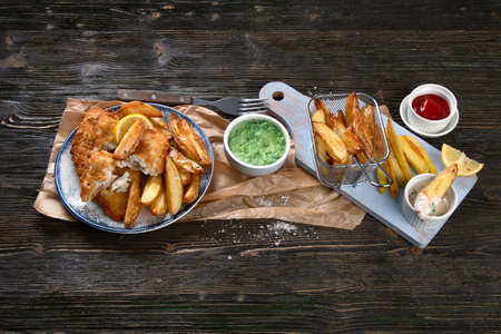 British traditional cuisine fish and chips. Served with mashed peas and different sauces.の写真素材
