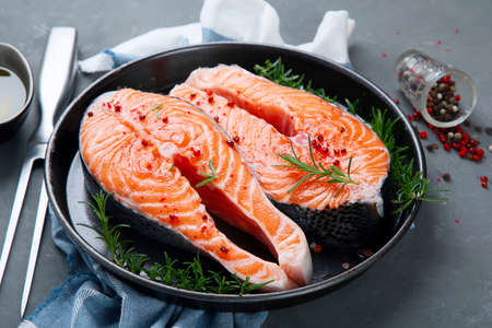 Fresh raw salmon steaks with herbs and oil. Ingredients for cooking.の写真素材