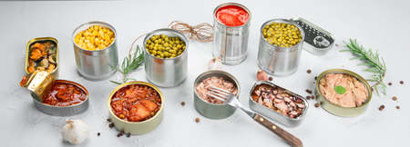 Various canned vegetables, fish and peas in aluminum cans. On light gray background. Top view, copy spaceの写真素材