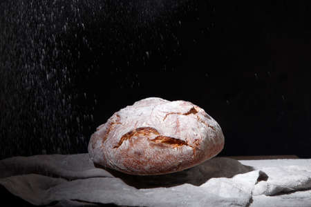 Fresh bread and buns on black background. Traditional bakery concept.
