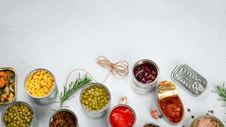 Various canned vegetables, fish and peas in aluminum cans. On light gray background. Top view, copy spaceの写真素材