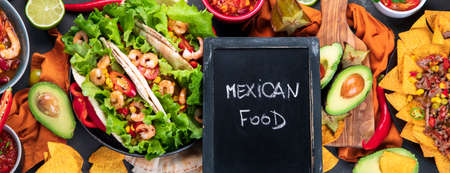 Delicious hispanic mexican meal board with nachos, tacos, guacamole, shrimps, avocado and starfruit....