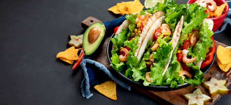 Delicious hispanic mexican meal board with tacos, guacamole, shrimps, avocado and starfruit. Hot and spicy. Copy space, panorama bannerの写真素材