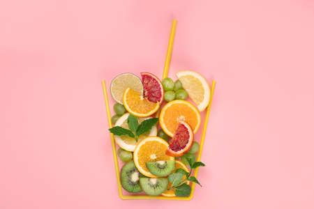 A glass made of differents fruits on colorful background. Minimalism design concept. Top view, copy spaceの写真素材