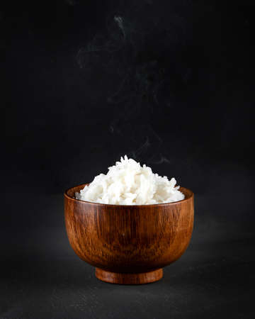Hot boiled jasmine rice with steam on black backgroundの写真素材