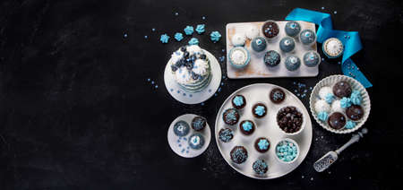 Delicious cake and cupcakes in blue on dark background. Table setting for celebration. Top view, copy spaceの写真素材