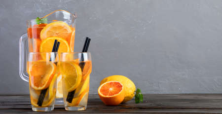 Refreshing orange lemonade on gray wooden table. Summer drinks concept. Front view, copy spaceの写真素材