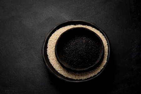 Black and white sesame seed on black background. Organic food concept Top view, Copy spaceの写真素材