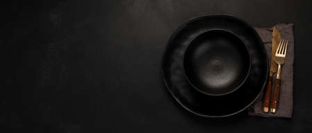 Table setting with a black plates on a black background. Minimalism concept. Top view, copy space, panoramaの写真素材