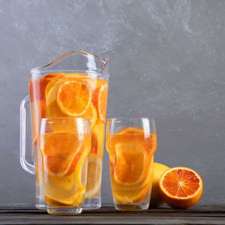 Refreshing orange lemonade on gray wooden table. Summer drinks concept. Top view, copy space
