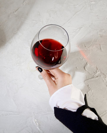 Young woman holding glass of red wine on white background. Hand with black polish.の写真素材
