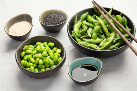 Raw edamame soya beans with salt and sauce on light gray background.の写真素材