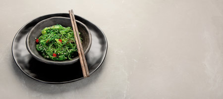 Wakame seaweed with sesame and chilli on gray background. Asian food concept. Copy space, panoramaの写真素材