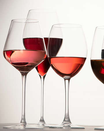 Red, rose and white wine in glasses on white backgroundの写真素材